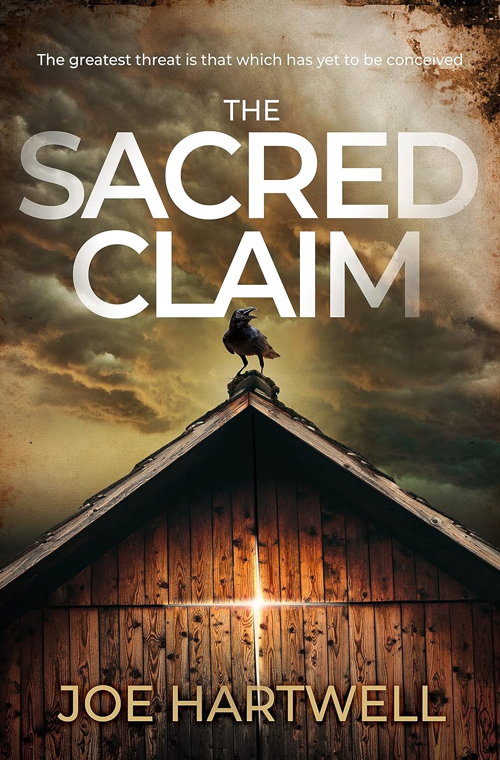 Cover of The Sacred Claim by Joe Hartwell: a crow perched on the peak of a wooden barn under a stormy sky, with a bright light shining through a crack in the boards.